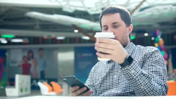 Człowiek za pomocą mobilnych i picia kawy w centrum handlowym — Wideo stockowe