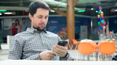 Genç bir adam onun smartphone bir alışveriş merkezi alışveriş merkezinde kullanın.