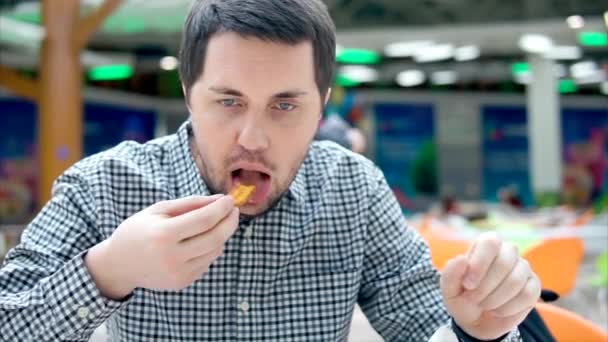 Un tipo comiendo papas fritas en la cafetería. Alimentos poco saludables y mucho colesterol . — Vídeos de Stock