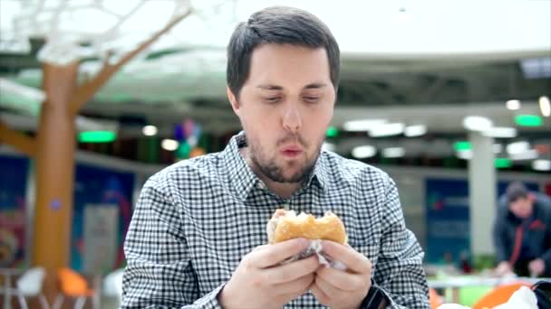 Muž na obědě s hamburger v nákupní centrum. — Stock video