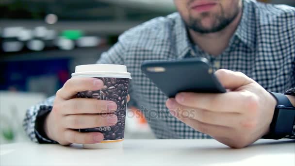 Крупним планом знімок рук чоловіка, який тримає телефон в руці і п'є каву . — стокове відео