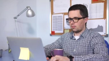 Klavyede yazarak, ekrana bakarak ve kahve içmek işadamı.