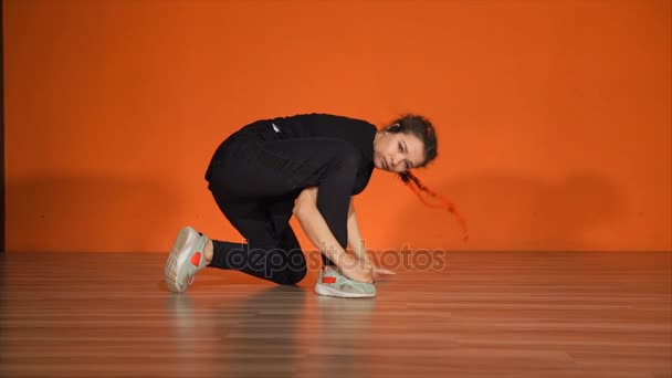 Mooie jonge vrouwelijke pauze danser tegen oranje muur in studio — Stockvideo