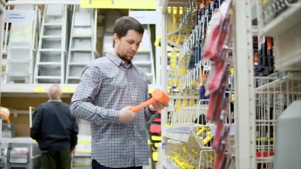 L'homme dans la quincaillerie choisit les outils. Il regarde le hummer en caoutchouc . — Video