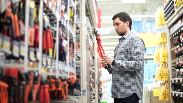 Een man die reparaties in zijn appartement kiest tangen in een bouw-winkel — Stockvideo