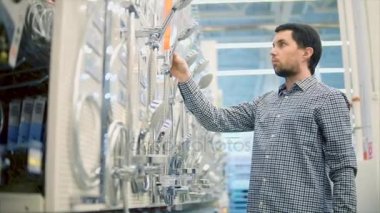 Genç bir adam alışveriş merkezinde bir duş için bir musluk satın alacak