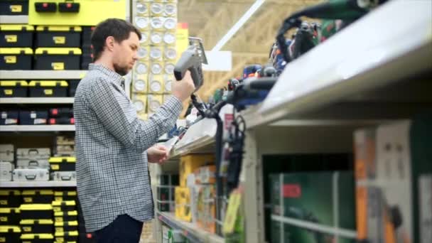 Een jongeman gaat kopen van een elektrische decoupeerzaag — Stockvideo