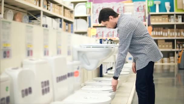 Νεαρός άνδρας εξετάζει την τουαλέτα στο τμήμα υδραυλικών στο εμπορικό κέντρο — Αρχείο Βίντεο