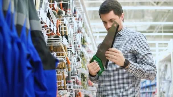 Homme examinant une scie à main dans un magasin d'outils — Video