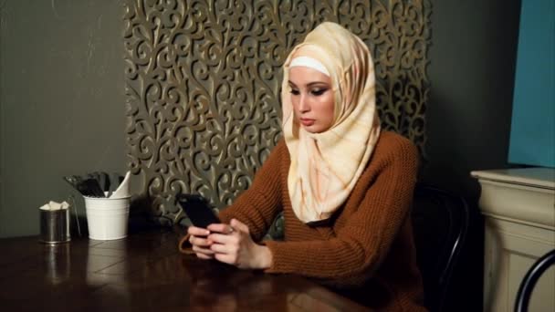 Une jeune femme arabe en hijab et des vêtements stricts communique avec son mari — Video