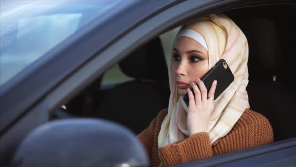 Una donna musulmana conduce uno stile di vita moderno, guidando un'auto e parlando al telefono — Video Stock