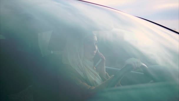 A young Arab woman is chatting on the phone with her husband in her personal car — Stock Video