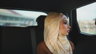 Bir arabanın arka koltuğunda bir hijab giyinmiş bir Müslüman kadın rides