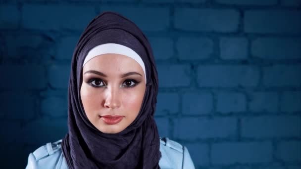 Retrato de una tranquila mujer musulmana moderna que lleva un hijab y una chaqueta de mezclilla — Vídeo de stock