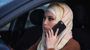 Direksiyon başında konuşmak bir telefon sahip Modern Müslüman kadın