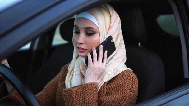 Muslimsk kvinna talar på mobilen i bilen — Stockvideo