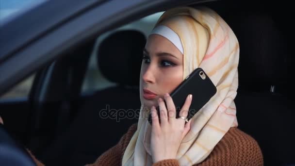Moderna muslimska kvinnan att ha en telefon prata vid ratten — Stockvideo