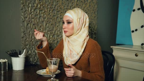 Muslim woman eating a dessert with coffee in cafe — Stock Video