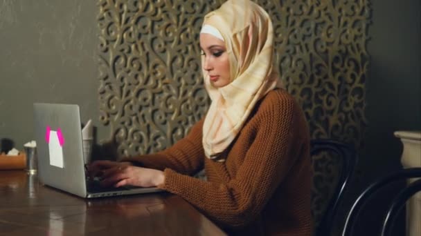 Mujer musulmana joven que trabaja por negocios con el ordenador portátil en la cafetería — Vídeo de stock