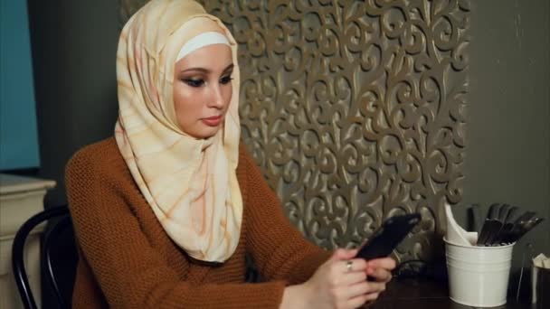 Muslim woman surfing the internet on mobile in cafe — Stock Video