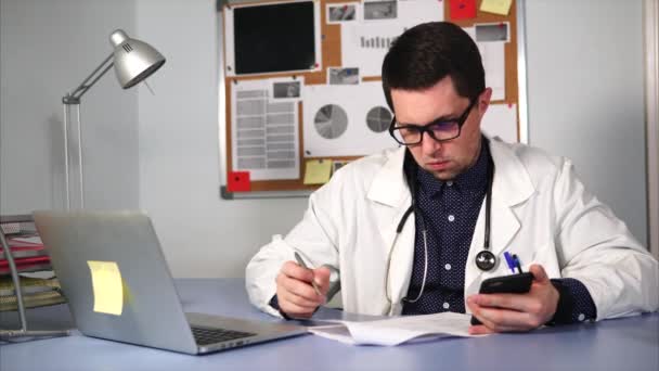 Ιατρικές βοηθός που εργάζεται στο χώρο εργασίας με το smartphone και ιατρικές φόρμες. — Αρχείο Βίντεο