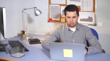 Ofis çalışanı iş başında. Masada oturan ve dizüstü bilgisayar kullanarak bir adam.