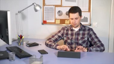 Ofis çalışanı ofisinde oturan tablet gelen postaları denetler.