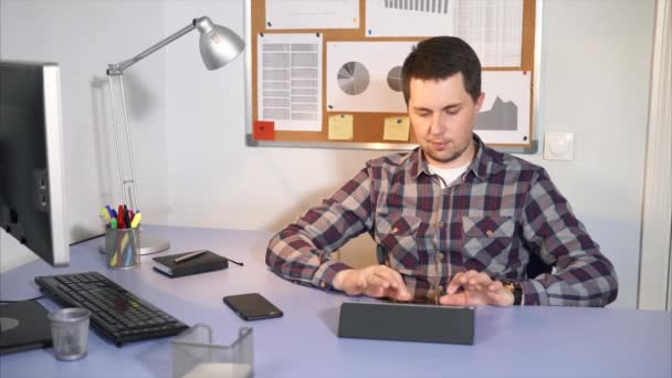 Работник офиса проверяет входящую почту на планшете, сидящем в его офисе . — стоковое видео