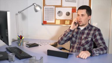 Ofisinde oturup onun müşteri ile bir cep telefonu üzerinde konuşurken işadamı.