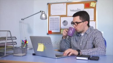 Dizüstü bilgisayarda yazdırma metin çay içme monitör bakarak ofis çalışanı