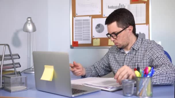 Homem ocupado preenche formulários de papel no local de trabalho e olha para o monitor do laptop — Vídeo de Stock