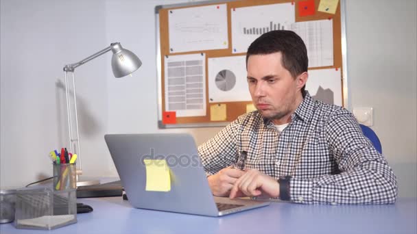 Ein Mann, der einen Vaporstift benutzt, schaut auf den Monitor des Laptops und antwortet per SMS — Stockvideo