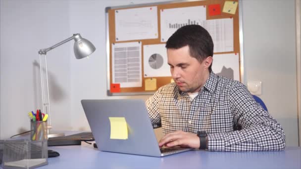 Уставший мужчина с нетерпением курит электронную сигарету, смотрит на ноутбук в офисе — стоковое видео