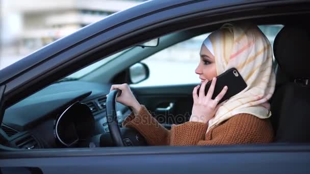 Σύγχρονη ζωή των μουσουλμάνων γυναικών. Γυναίκα οδήγηση αυτοκινήτου και να μιλάμε με smartphone. — Αρχείο Βίντεο