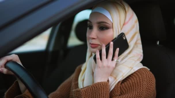 Muslimsk kvinna talar på mobilen i bilen — Stockvideo