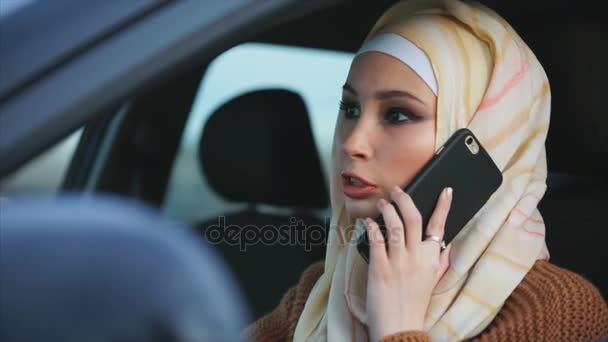 Mulher muçulmana no hijab com smartphone, dirige um carro . — Vídeo de Stock