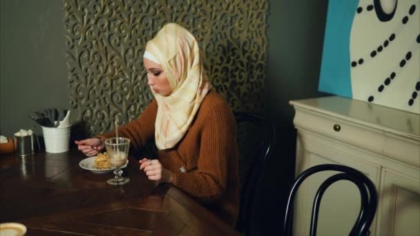 Muslim woman in hijab eats dessert in cafe. — Stock Video