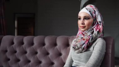 Parlak güzel hijab çekici Müslüman kadın kanepede oturuyor.
