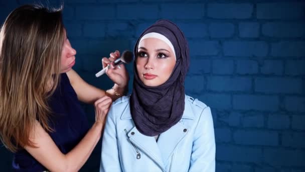 Le maquilleur fait un maquillage lumineux pour une femme arabe portant un foulard — Video