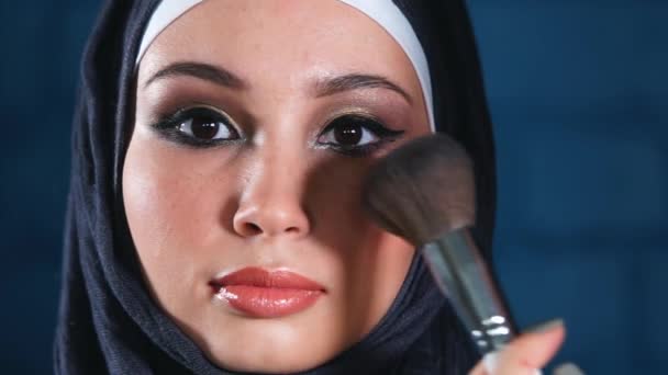 Muslimsk kvinna gör makeup på hennes ansikte med borste. — Stockvideo