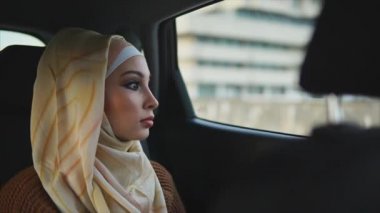 Bir arabanın arka koltuğunda bir hijab giyinmiş bir Müslüman kadın rides