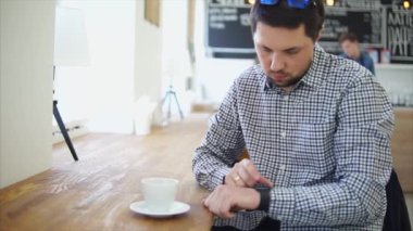 Yetişkin bir adam iletileri telefondan almak için akıllı bir saatini ayarlar