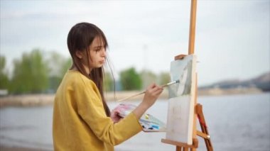 Genç kadın ressam bir şövale üzerinde bir Püskül manzara boyar, doğa üzerinde durmak