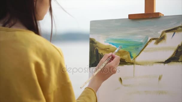 Woman artist paints an oil painting on canvas, which stands on an easel — Stock Video