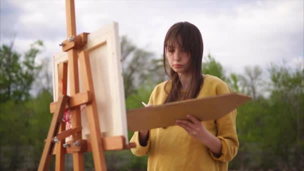 Una mujer adulta dibuja una naturaleza muerta sosteniendo una paleta con pinturas al óleo — Vídeo de stock