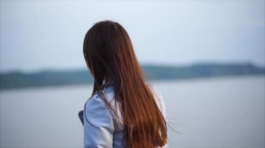 Kum ile ıssız bir kıyı boyunca ince bir genç modern giysiler içinde elini kolunu sallaya dönüyor