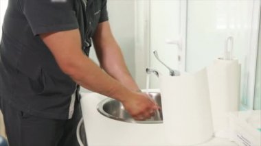 Yetişkin doktor dikkatle üzerinde lateks eldiven koymadan önce ellerini yıkar