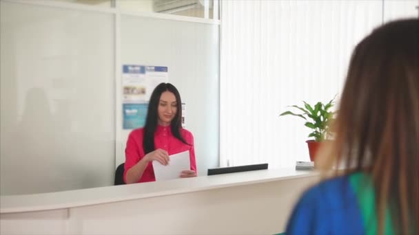 Una joven administradora amigable se reúne con una sonrisa invitada en una clínica dental — Vídeos de Stock