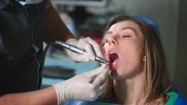 Klinikte diş hekimi tarafından diş beyazlatma, Doktor ağız boşluğu temizler.