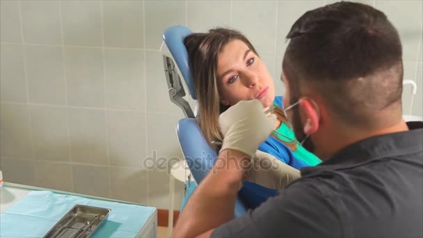 Ένας οδοντίατρος γιατρός λέει ένα νεαρό ασθενή τι θα κάνει με το στόμα του γυναικείου — Αρχείο Βίντεο